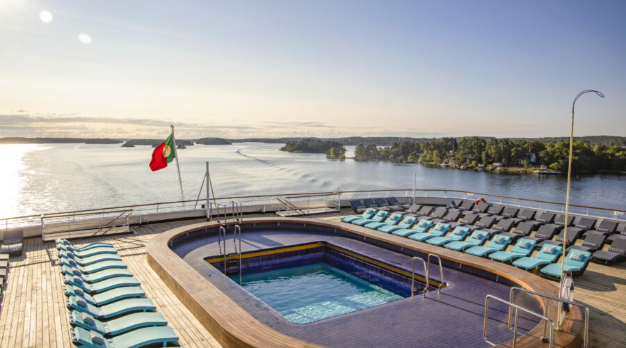 Oasis Pool with lounge chairs on Navigator Deck of cruise ship Vasco da Gama (nicko cruises) during passage of Stockholm Archipelago, near Stockholm, Sweden